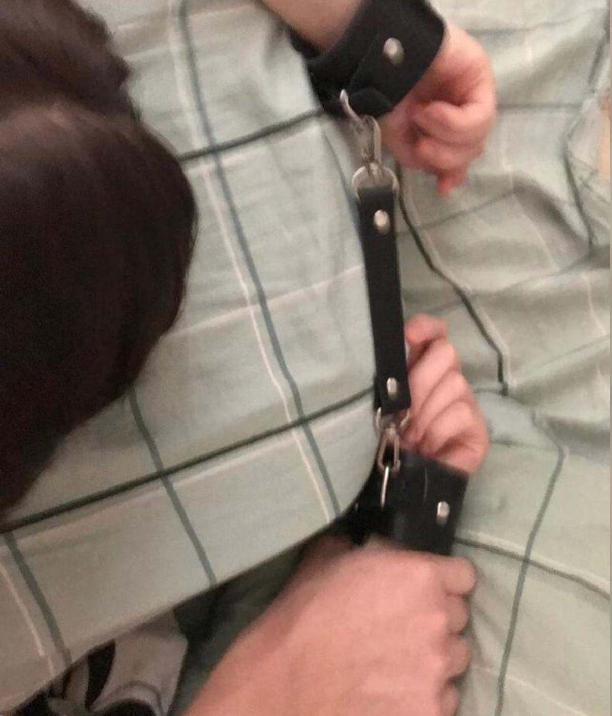 Adjustable black wrist cuffs connected by a detachable strap.