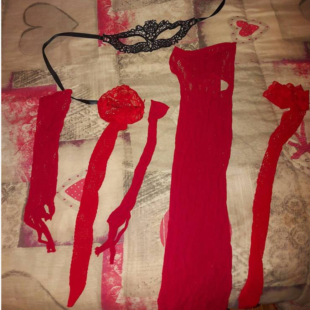Flat lay of a red sheer lace lingerie dress with matching lace gloves and eye mask